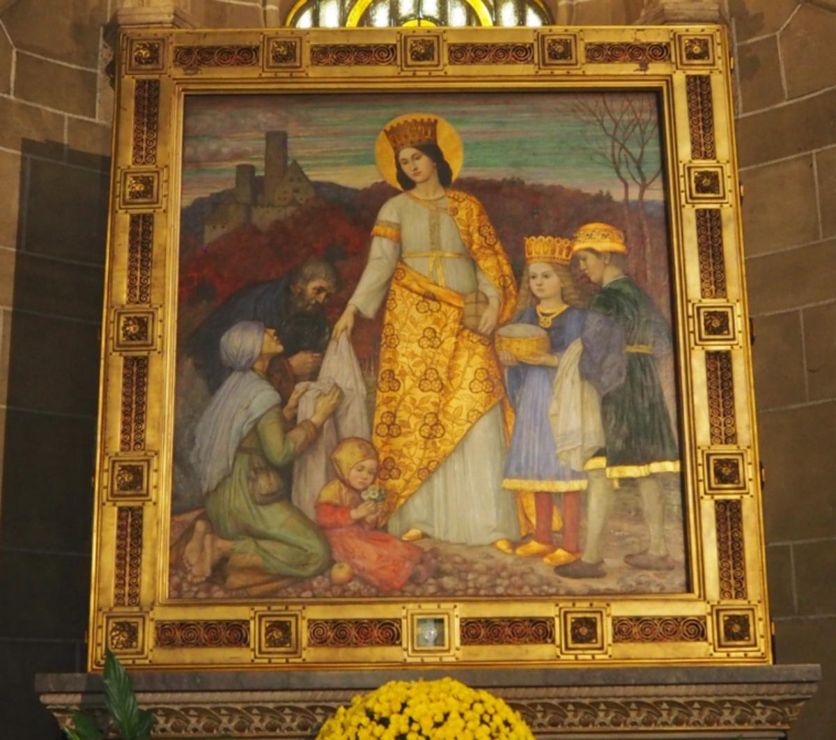 Elisabeth-Altar von Matthäus Schiestl. Der Elisabeth-Altar im nördlichen Seitenchor entstand 1915.  Er zeigt die Markgräfin von Thüringen Elisabeth, wie sie mit ihren beiden Kindern Brot und Kleidung an die Armen verteilt.  Elisabeth von Thüringen (* 1207[1] in Pressburg oder auf Burg Rákóczi in Sárospatak (Ungarn); † 17. November 1231 in Marburg an der Lahn), auch Elisabeth von Ungarn genannt, war eine ungarische Prinzessin, deutsche Landgräfin, ist Heilige der katholischen Kirche und galt als „deutsche Nationalheilige“. Ex-Bild-DB-ID: 27078